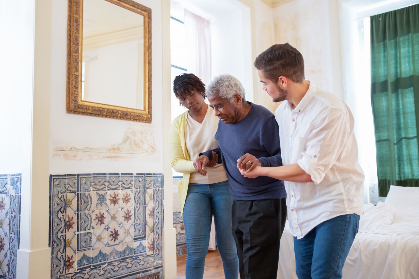 Two caring team members gently assisting an older gentleman as he walks
