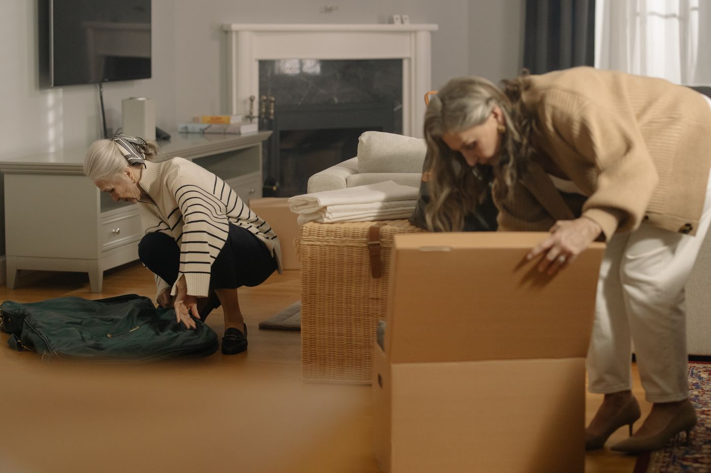 Older women receiving thoughtful help while sorting and packing belongings at home